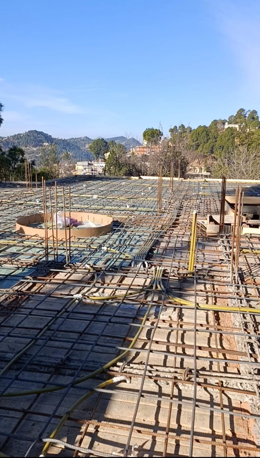 A reinforced slab laid out with conduit before a pour, hills beyond